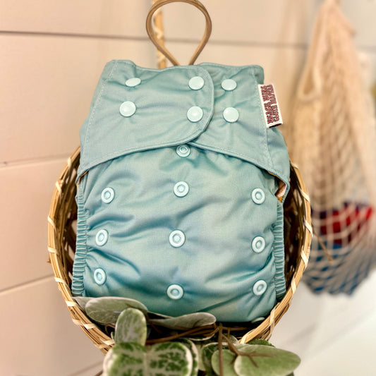 front of pocket cloth diaper with adjustable rise snaps, in a basket 